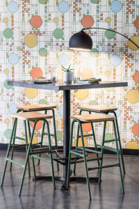 Olive Green Bar Stools against patterened wallpaper inside of a restaurant