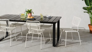 Black outdoor dining table with white outdoor stacking chairs