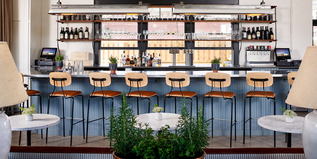 Reece Barstools with upholstered seat and black frame at restaurant bar.