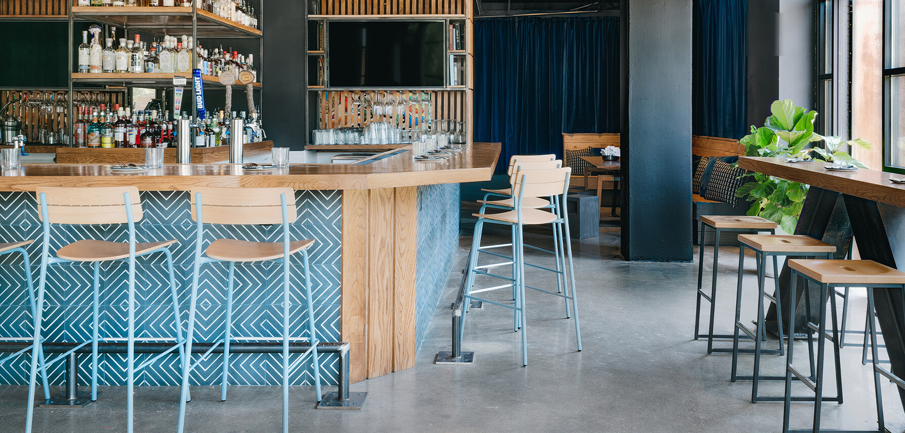 Bar featuring Sherman bar stools with light blue base and natural wood seat.