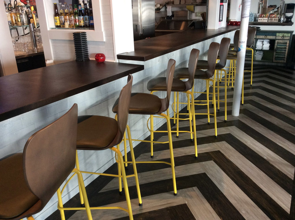 Row of Felix Jr. Barstools with wood shell and yellow legs.