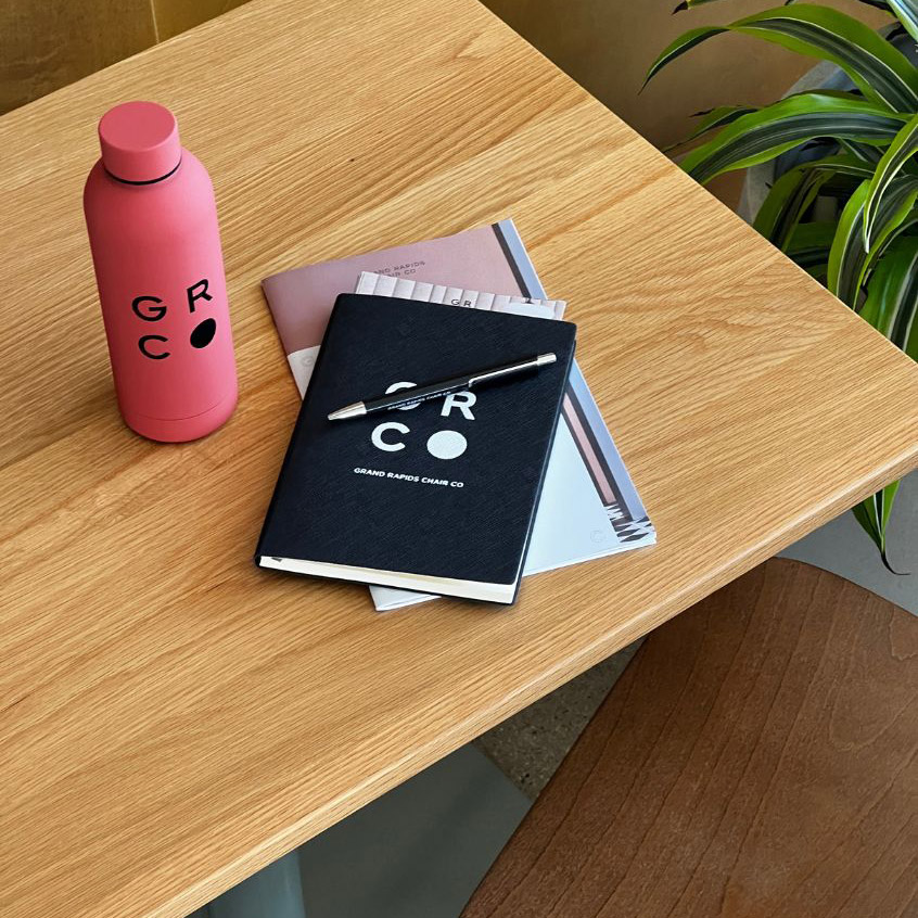 Grand Rapids Chair notebook and water bottle atop an Onesima Pedestal Table