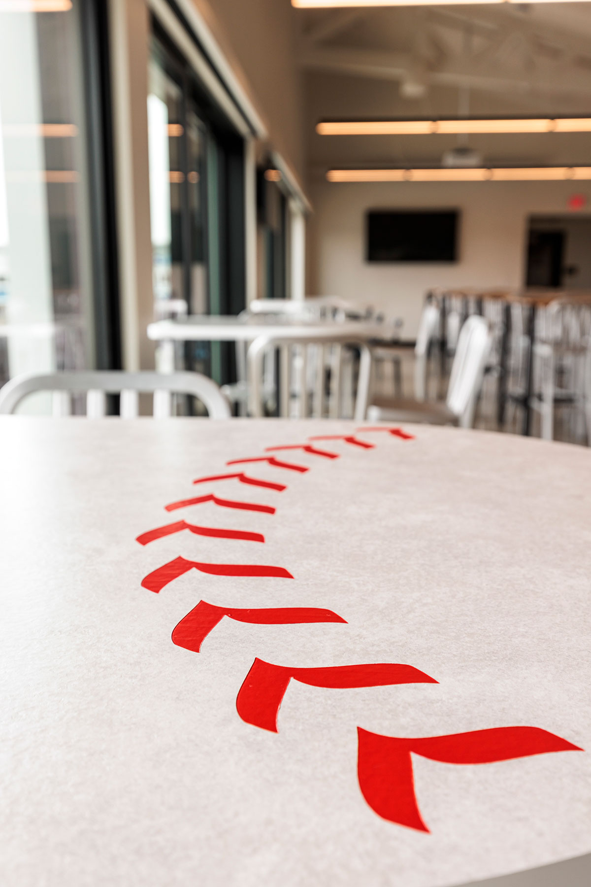 An Onesima Pedestal Table with a cheeky nod to the game—baseball laces engraved right into the laminate and filled in with classic red. Photo by Carbon Stories.